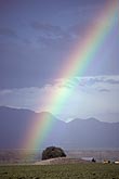 A bright, colorful rainbow arc descends in front of distant mountains