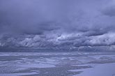 Brooding sky over a freezing lake with ice cover