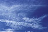 Excited swirling cloud wisps in a bright blue sky