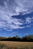 Cloud wisps dance across an intensely bright blue sky