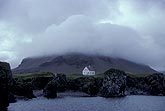 Dense gray cloud snugly wraps a mountain top in a remote landscape