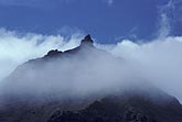 Clouds veil a volcanic mountain in enchantment and mystery