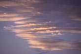 Slender cloud strips glow with brilliant sunset light
