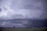 A dark low cloud creeps in on a lonely farm landscape